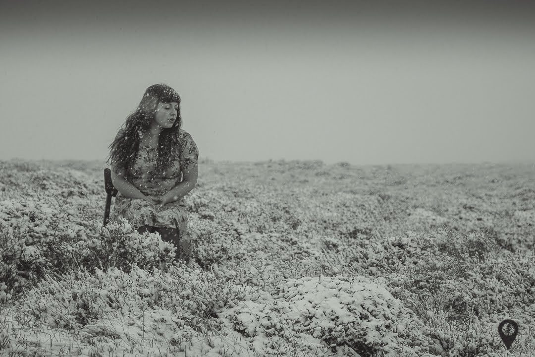 Black and white: a child crouching alone in a wide, empty field