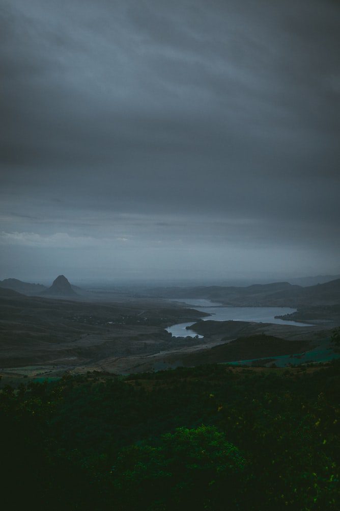 A dark green highland valley with a river winding through it under low cloud