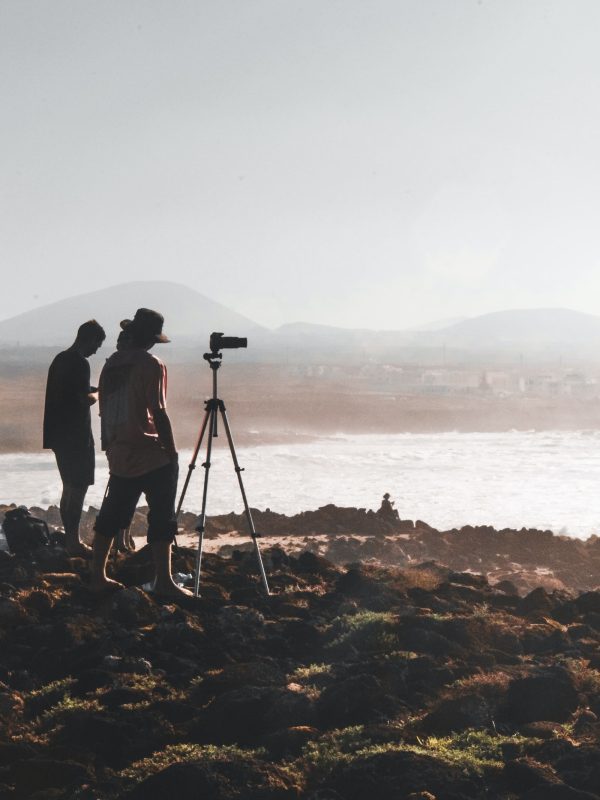 Two photographers with a tripod on a rocky headland in mist