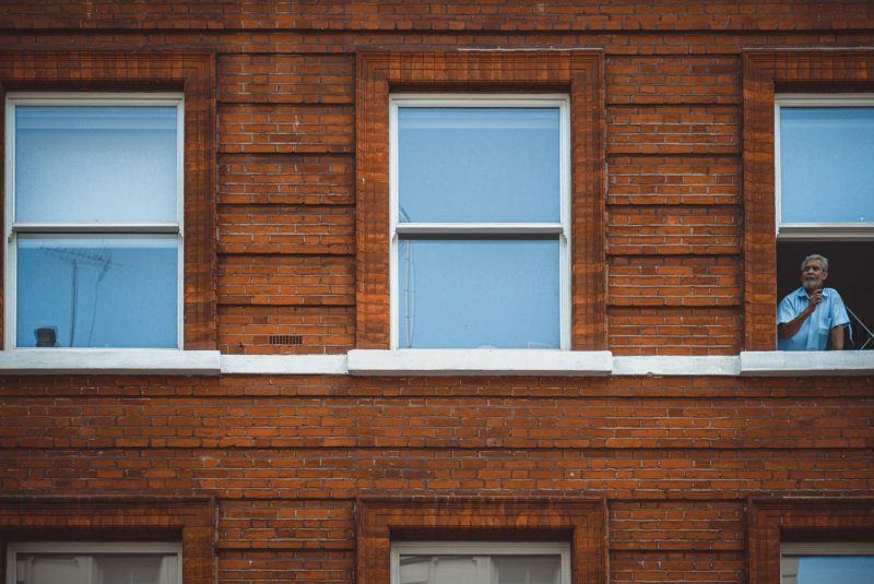 A man leaning out of an upper window of a red brick building