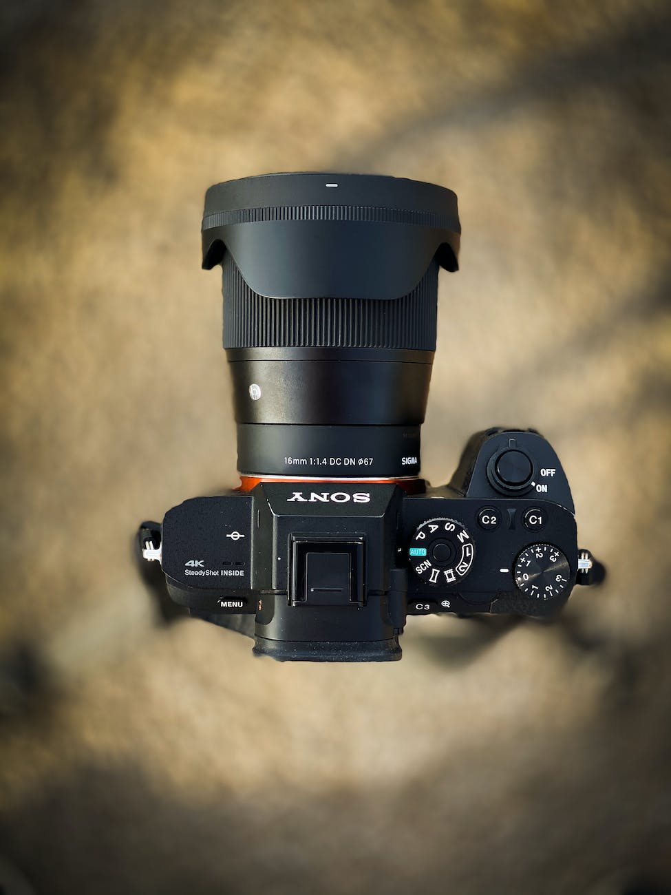 A mirrorless camera seen from above against a warm brown background