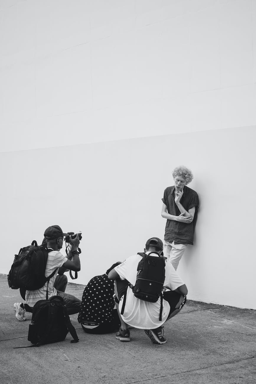 Black and white: photographers crouching to shoot a woman against a plain wall
