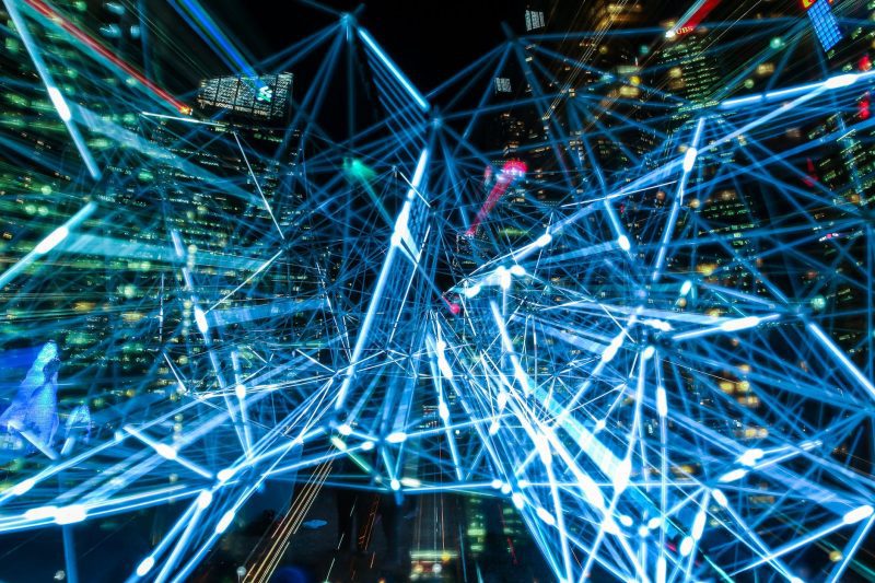 An abstract network of glowing blue lines over a city at night