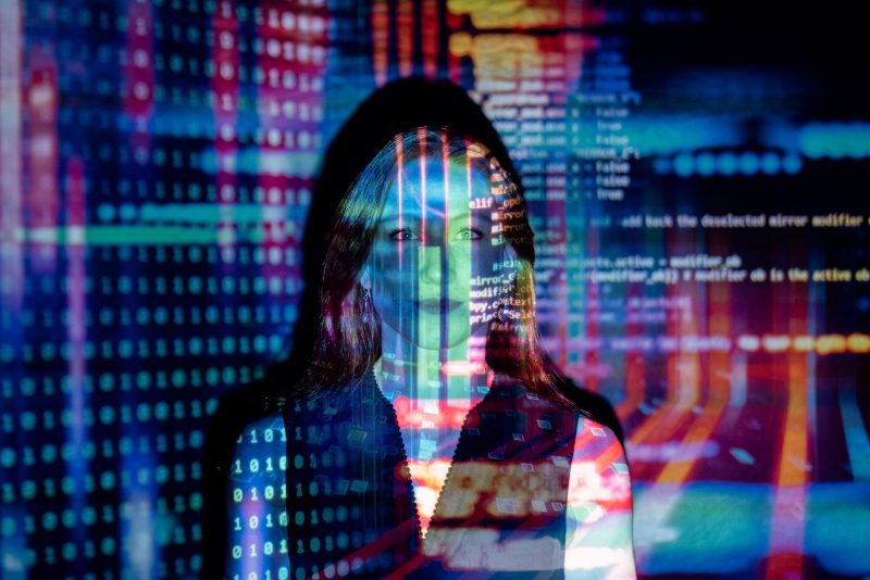 A woman's face overlaid with columns of code and coloured static