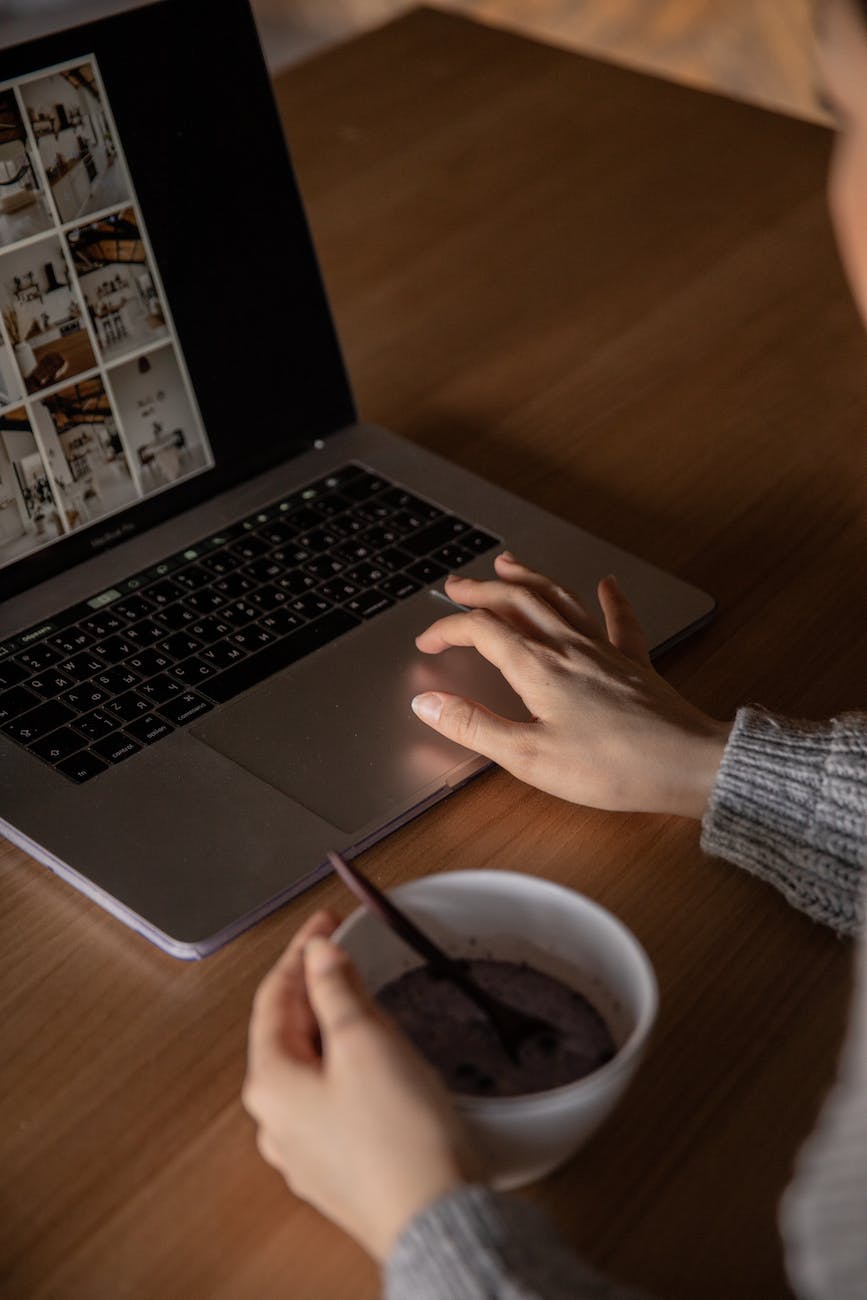 Someone working at a laptop with a cup of coffee, seen over their shoulder