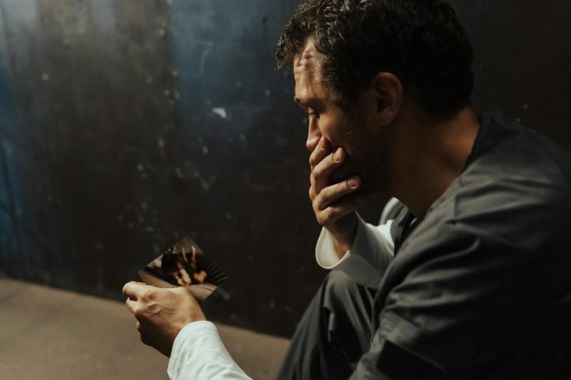 a sad man looking at a photo of a child
