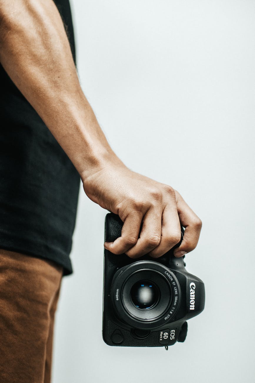 a mans hand holding a Canon DSLR 6D camera