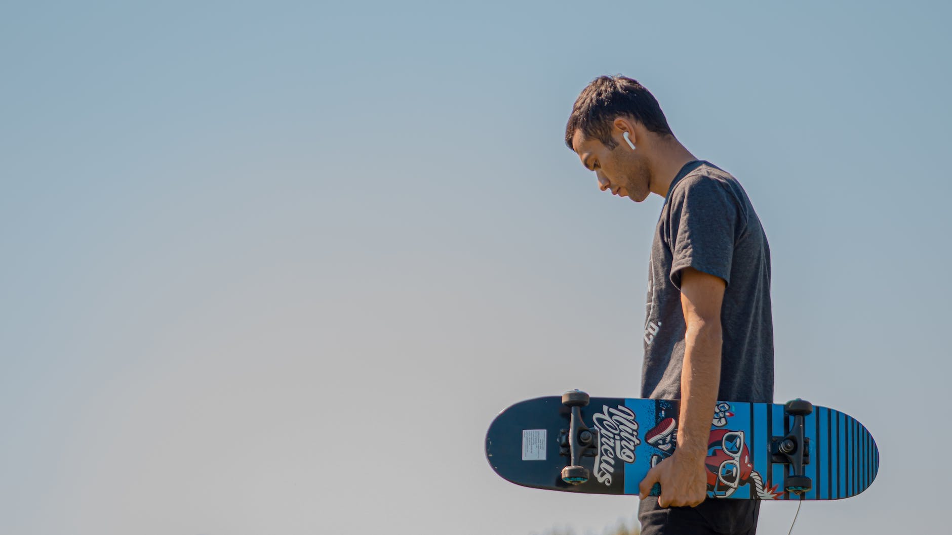 a man holding a skateboard with airpods in his ear