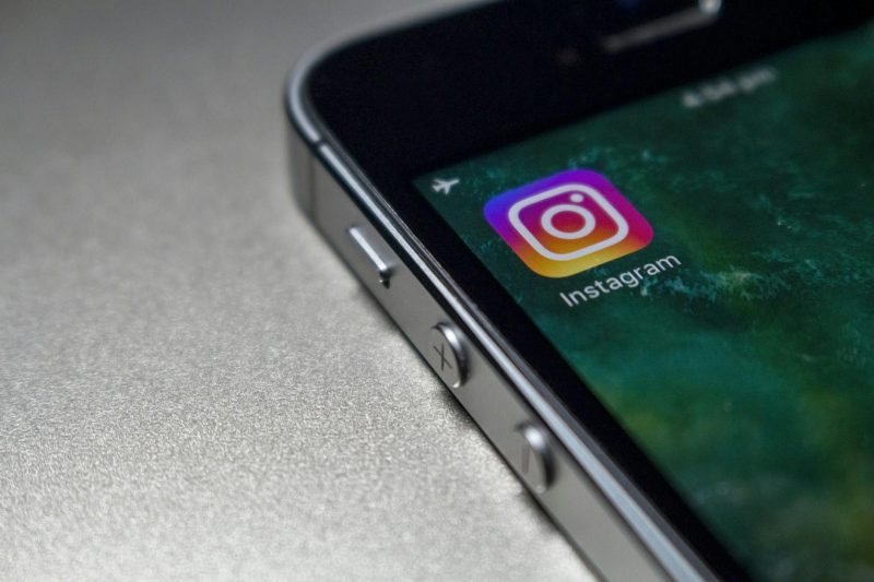 A phone held at an angle, a photo-sharing app open on the screen
