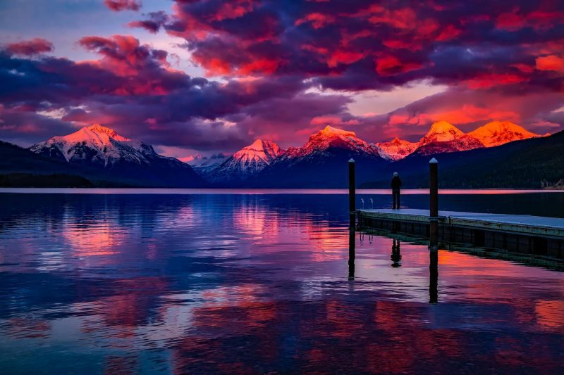 a mountain scene in with a lake in front at sunset