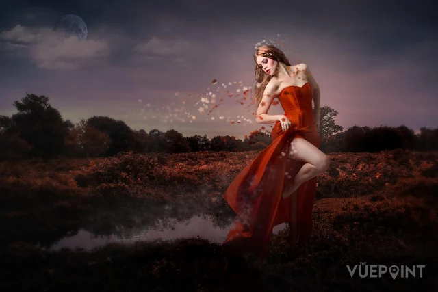 A figure in a red dress dissolving into the air above a field
