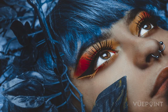 A close portrait with blue feathers and bold eye make-up