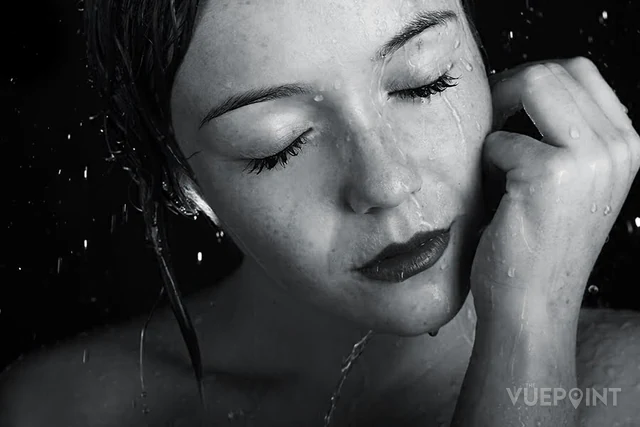A close black and white portrait, water on the face