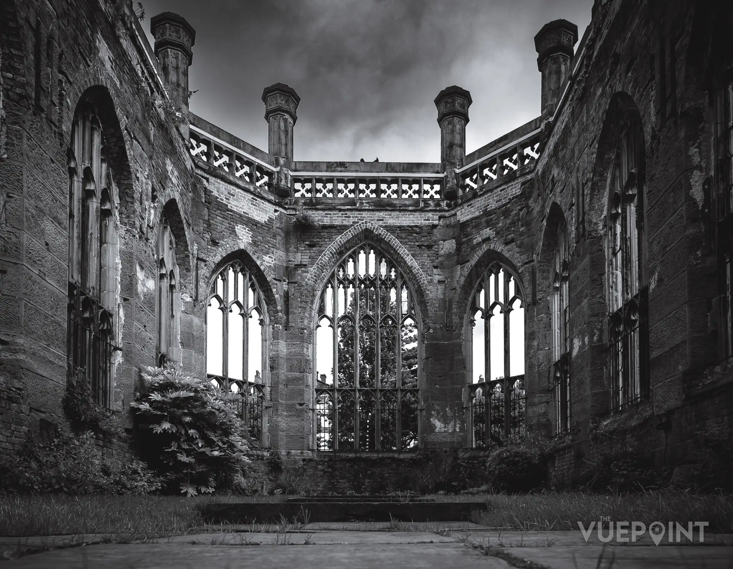 The inside of a ruined church, open to the sky, in black and white