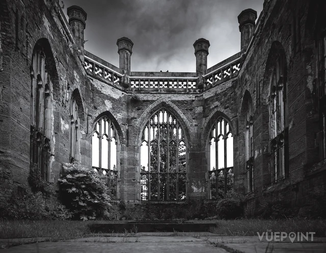The inside of a ruined church, open to the sky, in black and white