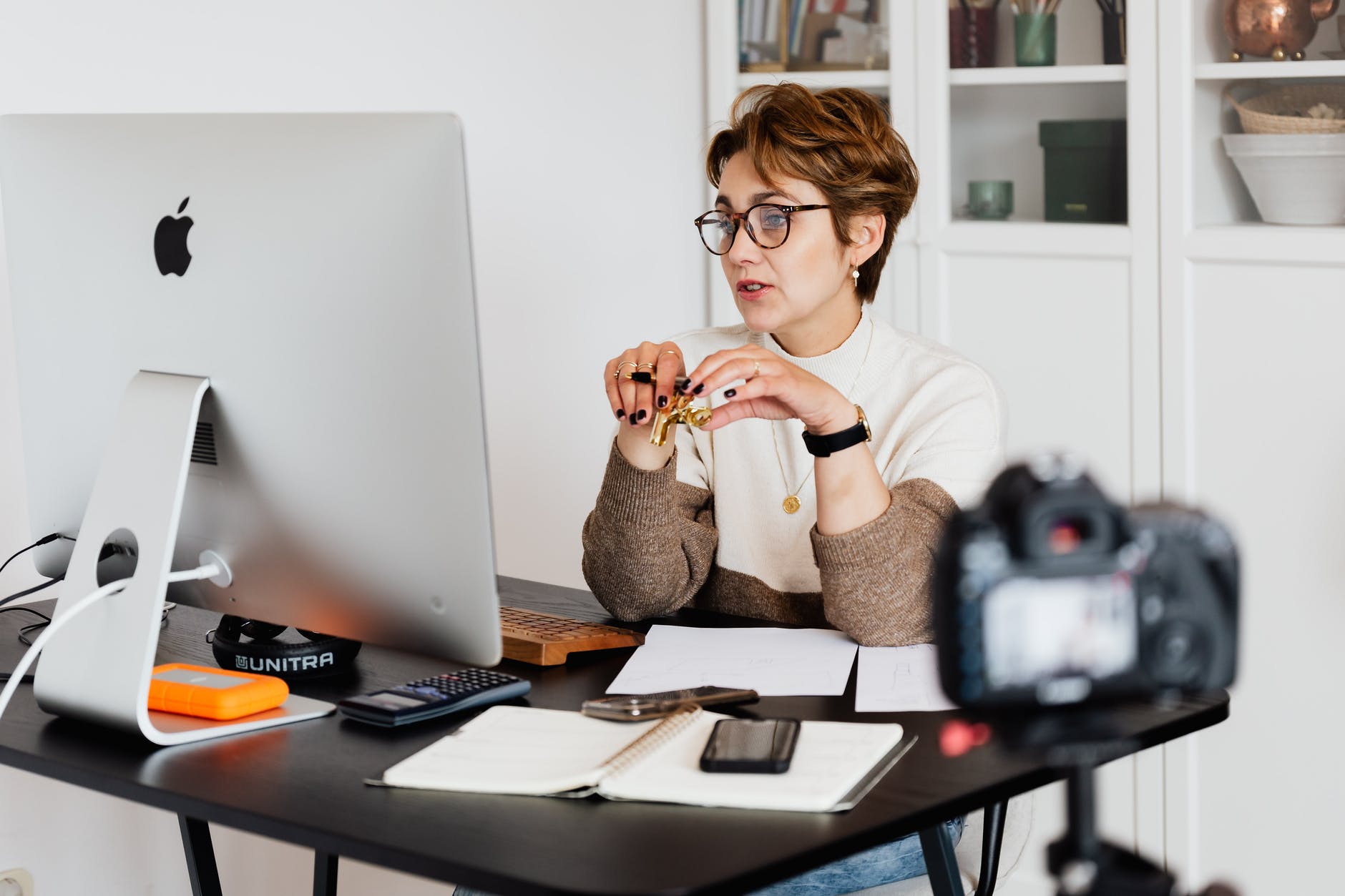 lady wearing glasses sat at her large computer screen with a clip and pen in her hand