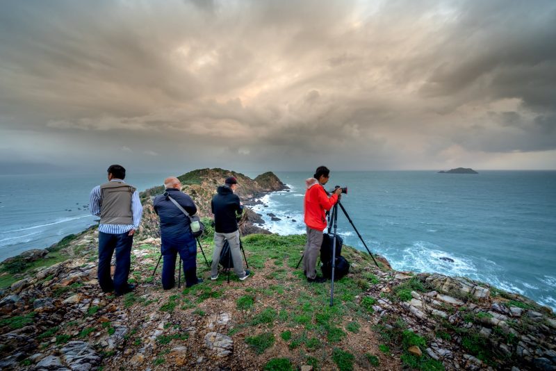 photographers on sea shore under clouds