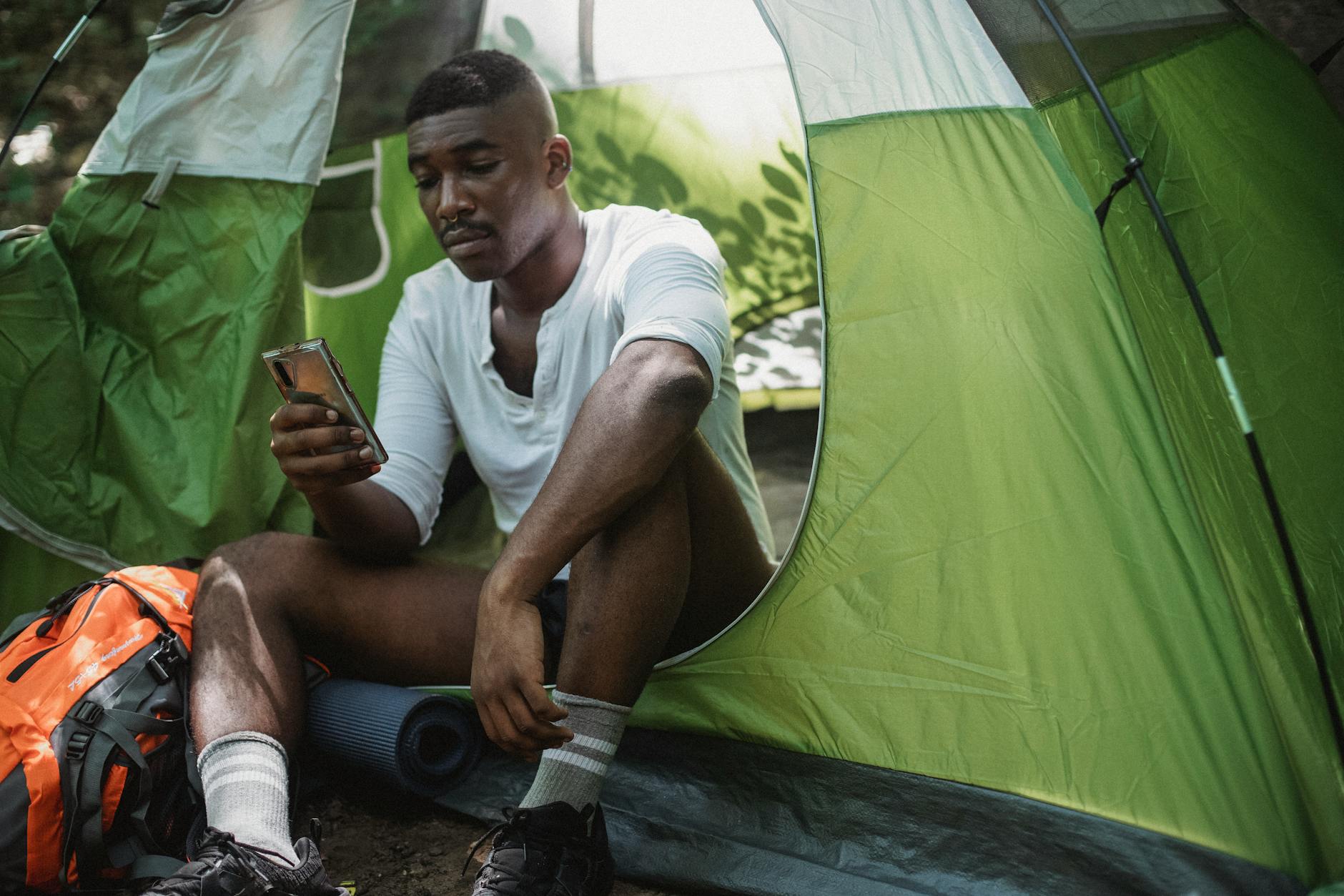 a sad man in a tent looking at his phone
