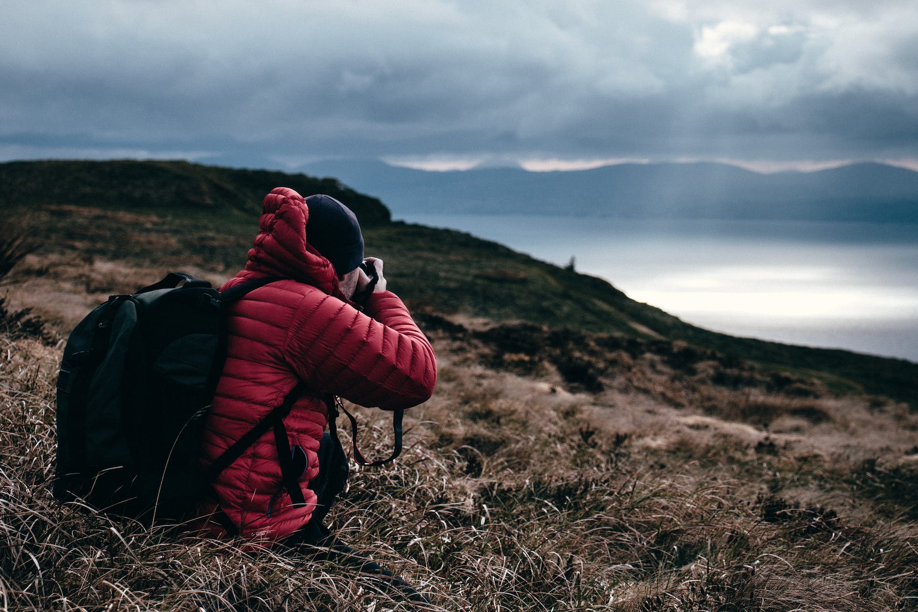 a photographer in a red coat taking a photo of a landscape