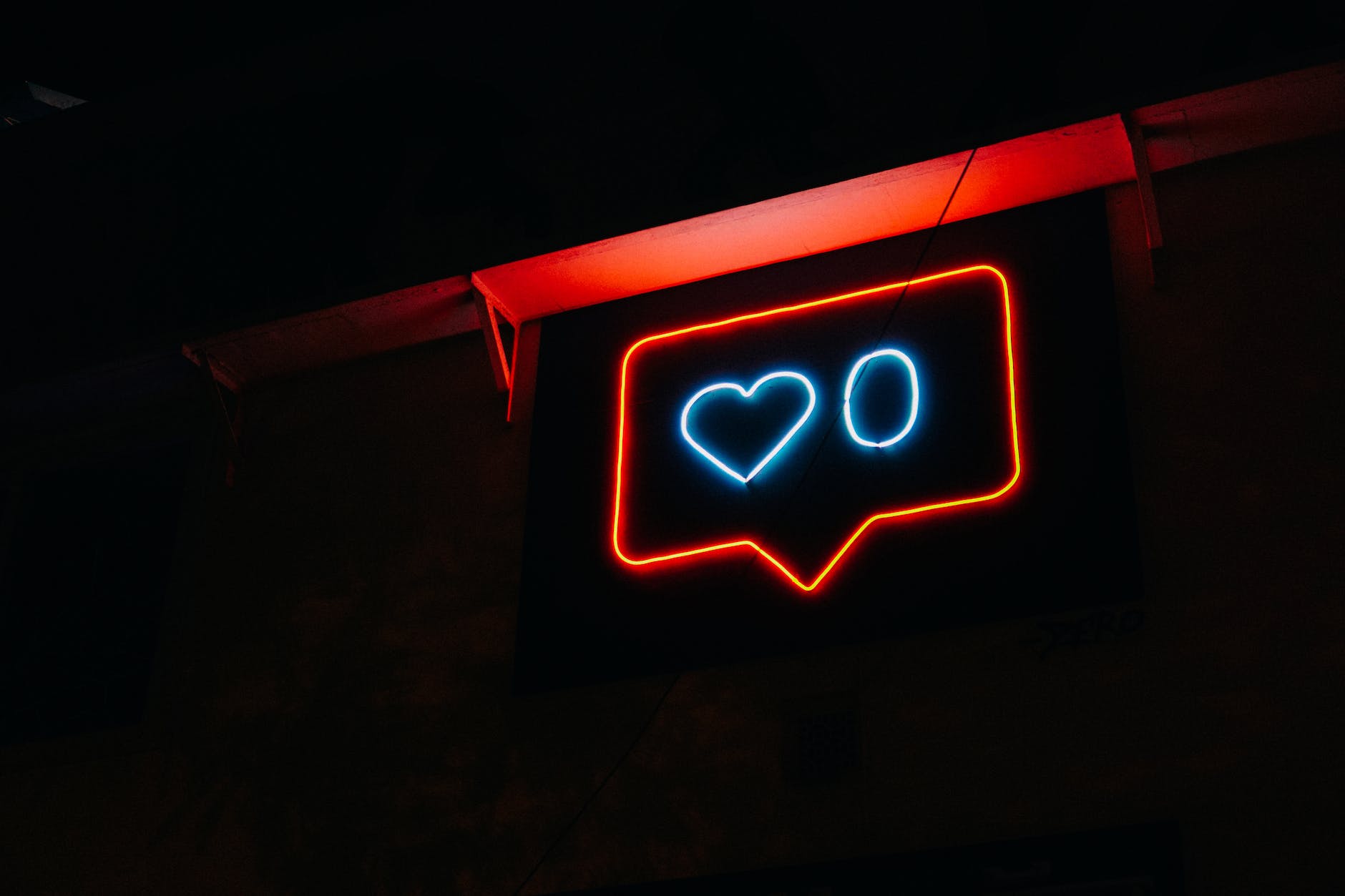 a neon light in the shape of an instagram reaction with 0 hearts
