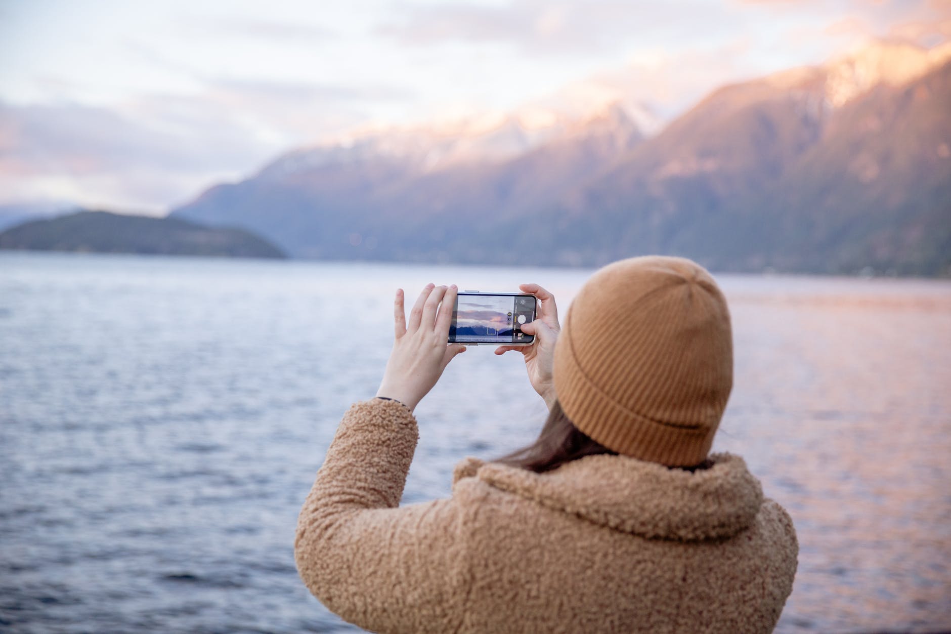 a lady taking a photo of a lake with her iphone