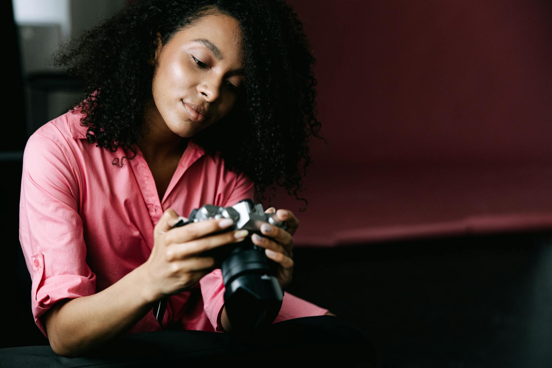 a female photographer in a pink shirt looking at the back of a camera