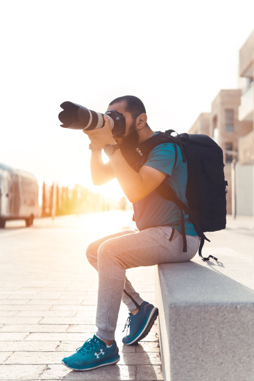 A man sat on a granite stone taking photos at golden hour
